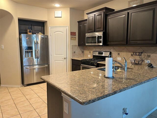 14125 Rabbit Brush Ln, Fort Worth, TX 76052 - kitchen featuring appliances with stainless steel finishes, tasteful backsplash, a peninsula, and dark stone counters