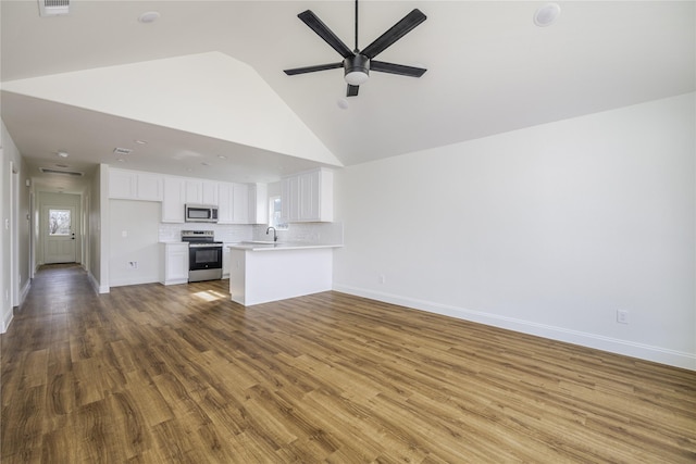 kitchen with wood-type flooring, kitchen peninsula, white cabinets, stainless steel appliances, and backsplash