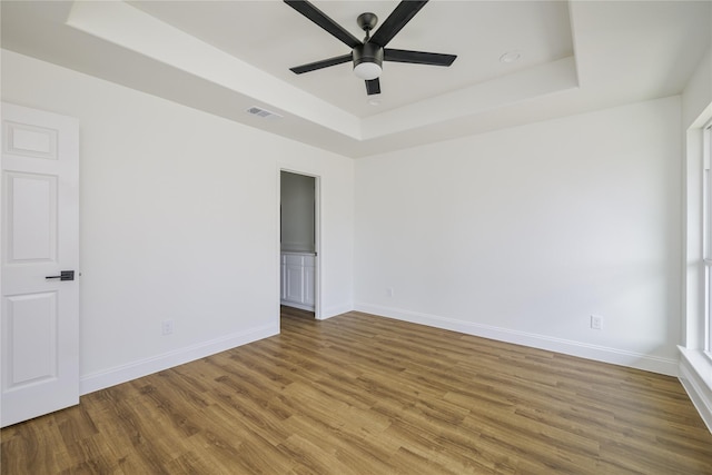 empty room featuring hardwood / wood-style floors, a tray ceiling, and ceiling fan