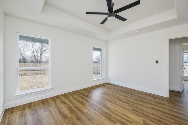 unfurnished room featuring ceiling fan, a tray ceiling, and dark hardwood / wood-style flooring