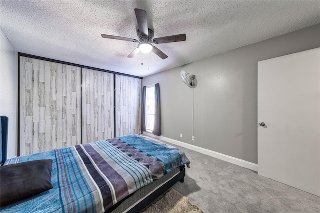 bedroom with ceiling fan, carpet floors, and a textured ceiling