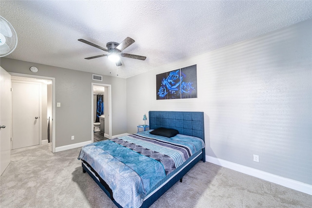 carpeted bedroom featuring ceiling fan, a textured ceiling, and ensuite bath