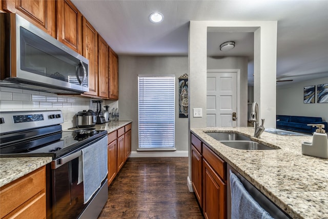 kitchen with light stone counters, appliances with stainless steel finishes, sink, and tasteful backsplash