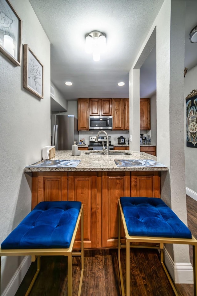 kitchen featuring sink, stainless steel appliances, a textured ceiling, dark hardwood / wood-style flooring, and kitchen peninsula