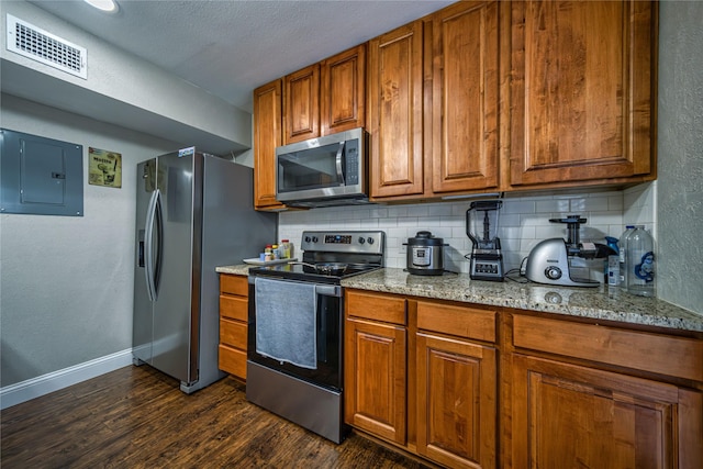 kitchen featuring light stone counters, stainless steel appliances, electric panel, and backsplash