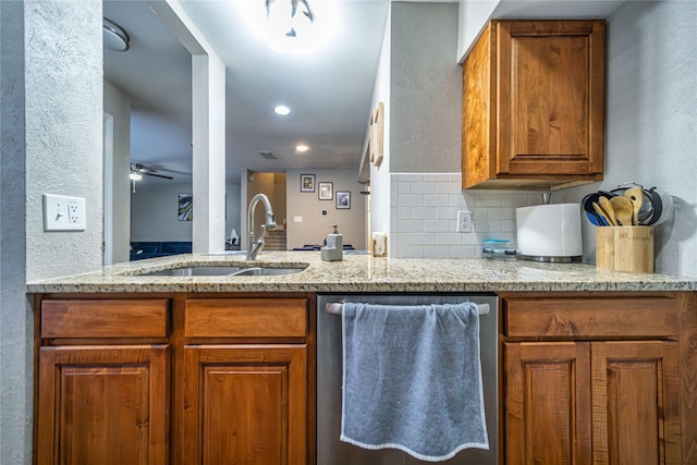 kitchen featuring sink, dishwashing machine, ceiling fan, light stone countertops, and decorative backsplash