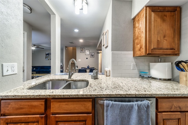 kitchen featuring sink, decorative backsplash, light stone countertops, and ceiling fan