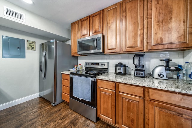 kitchen featuring stainless steel appliances, electric panel, light stone countertops, and backsplash