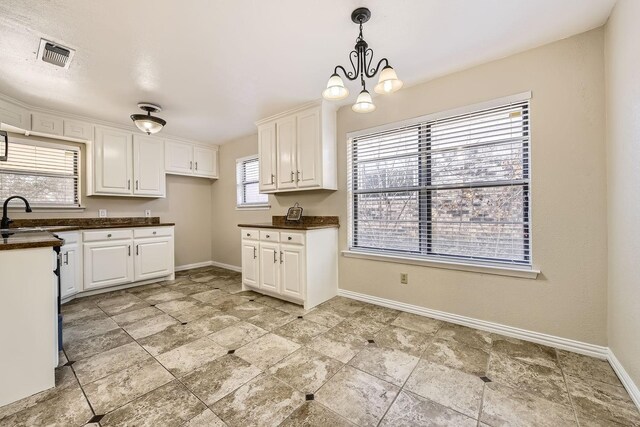 kitchen featuring white cabinetry, sink, decorative light fixtures, and an inviting chandelier