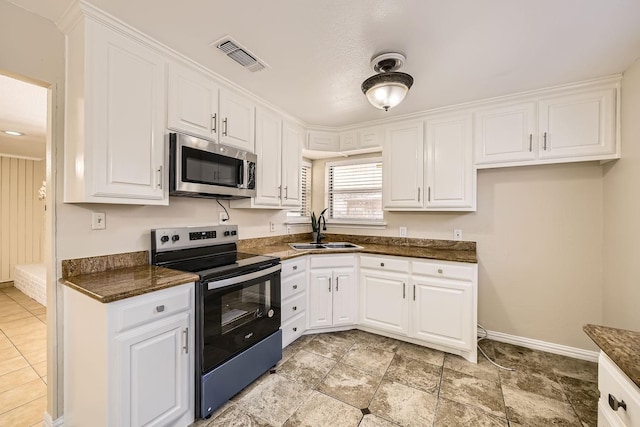 kitchen featuring sink, dark stone counters, white cabinets, and appliances with stainless steel finishes