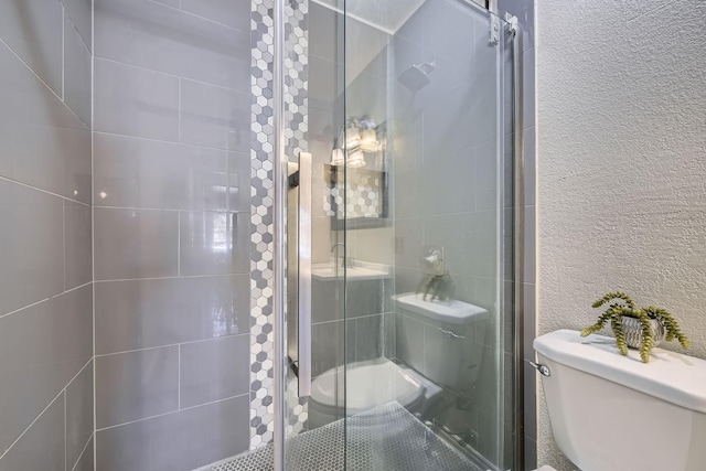 bathroom with toilet and a shower with shower door