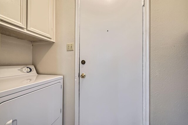 clothes washing area featuring cabinets and washer / dryer