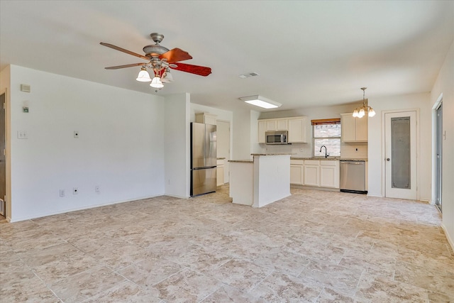 kitchen featuring pendant lighting, ceiling fan, stainless steel appliances, and a center island