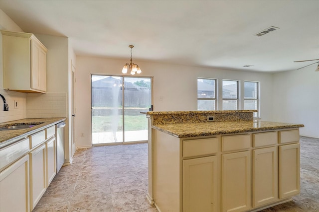 kitchen with sink, decorative light fixtures, stainless steel dishwasher, cream cabinets, and backsplash