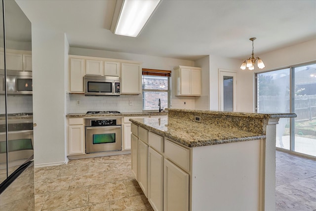 kitchen featuring tasteful backsplash, a center island, hanging light fixtures, stainless steel appliances, and light stone countertops