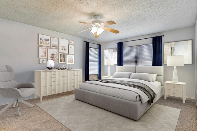 bedroom with ceiling fan, light carpet, and a textured ceiling