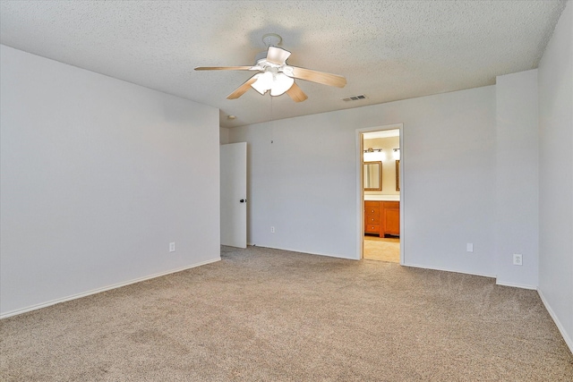 spare room featuring ceiling fan, light colored carpet, and a textured ceiling