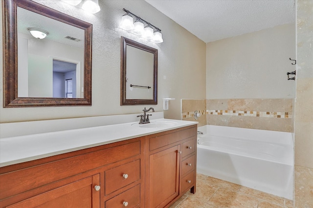 bathroom featuring vanity, a textured ceiling, and a tub