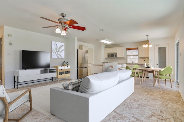 living room with ceiling fan with notable chandelier