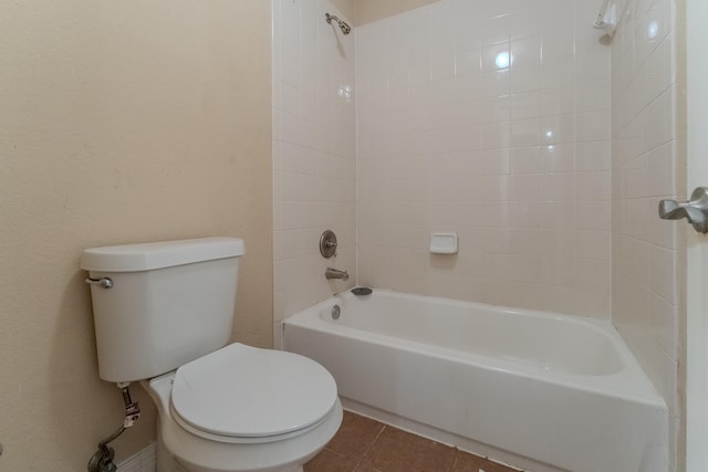 bathroom featuring tile patterned flooring, tiled shower / bath, and toilet