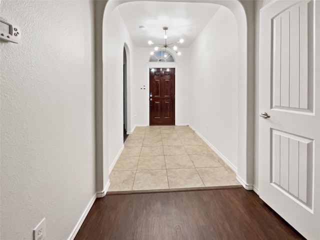 corridor featuring a notable chandelier and light wood-type flooring