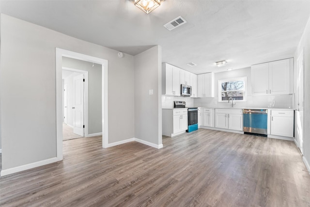 kitchen with light wood-type flooring, appliances with stainless steel finishes, sink, and white cabinets