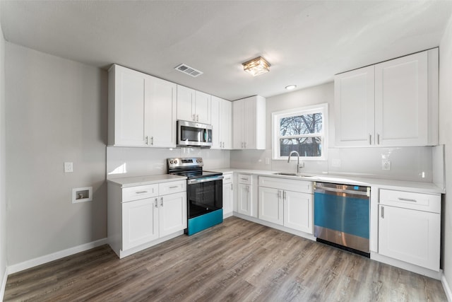 kitchen featuring stainless steel appliances, white cabinetry, sink, and light hardwood / wood-style floors