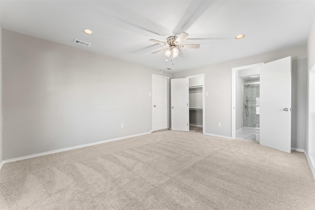 unfurnished bedroom with ceiling fan, connected bathroom, light carpet, a walk in closet, and a closet