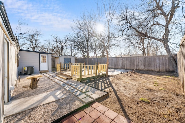 view of yard with central AC unit, a deck, and a storage unit