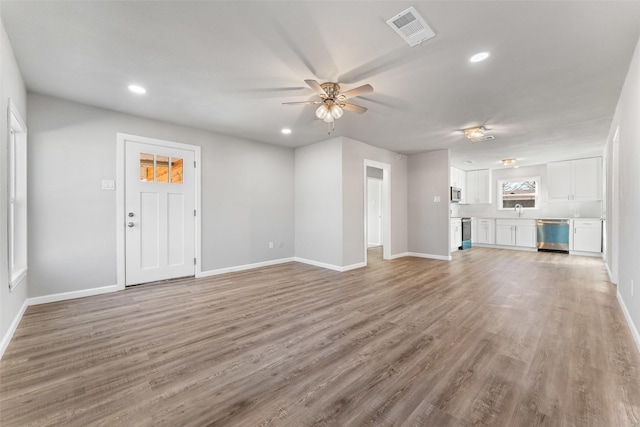 unfurnished living room featuring hardwood / wood-style floors, sink, and ceiling fan