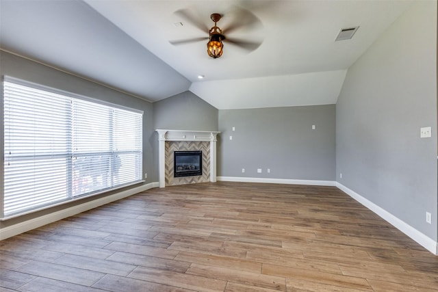 unfurnished living room featuring vaulted ceiling, ceiling fan, a tiled fireplace, and light hardwood / wood-style floors