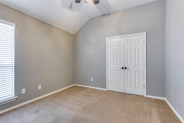 unfurnished room featuring a healthy amount of sunlight, ceiling fan, lofted ceiling, and light carpet