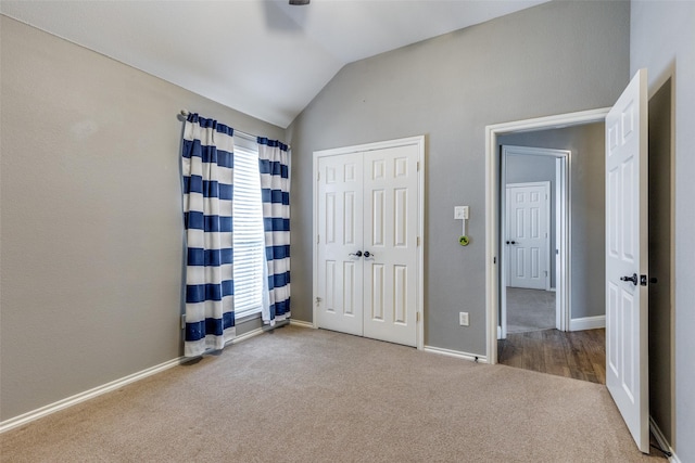 unfurnished bedroom with lofted ceiling, carpet flooring, ceiling fan, and a closet