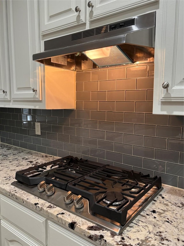 kitchen with white cabinetry, tasteful backsplash, light stone countertops, and stainless steel gas stovetop