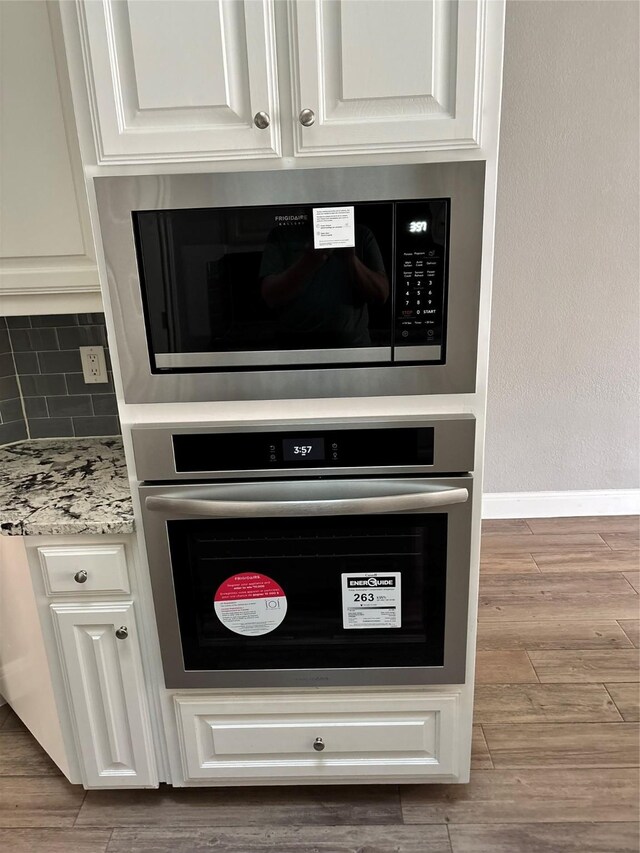 details with wall oven, white microwave, and white cabinets