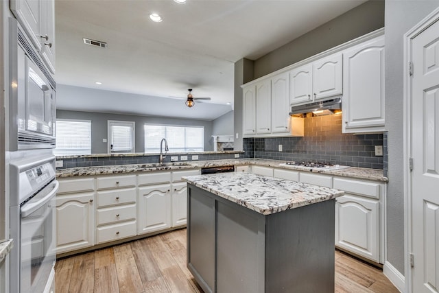 kitchen featuring a kitchen island, white cabinets, white appliances, kitchen peninsula, and light wood-type flooring