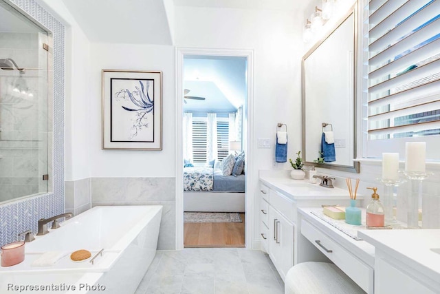 bathroom featuring vanity, a tub, and tile walls