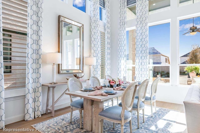 dining space with hardwood / wood-style flooring, a high ceiling, and ceiling fan