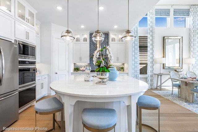 kitchen featuring appliances with stainless steel finishes, white cabinets, and decorative light fixtures