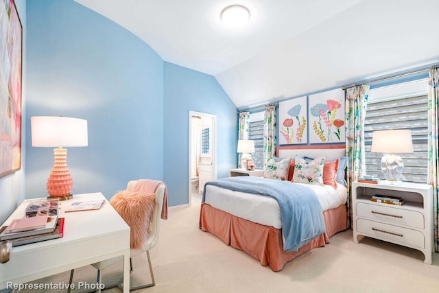 bedroom with lofted ceiling, light carpet, and connected bathroom