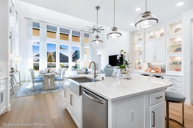 kitchen with sink, dishwasher, an island with sink, and white cabinets