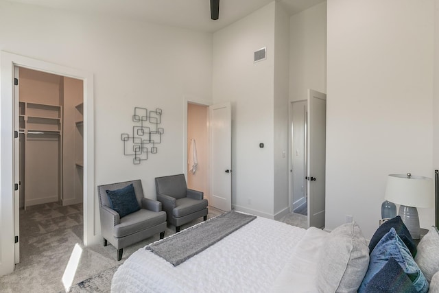 carpeted bedroom featuring a walk in closet, a closet, and a high ceiling