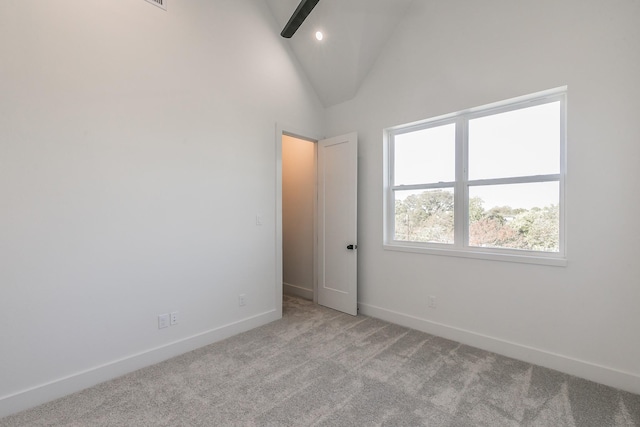 spare room with high vaulted ceiling and light colored carpet