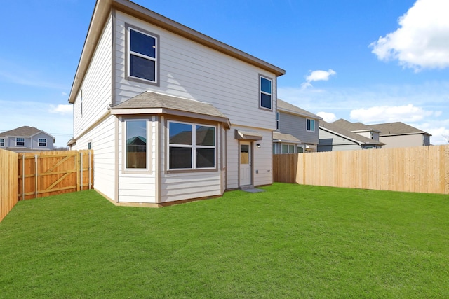 back of house with a fenced backyard and a yard