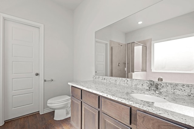 full bath featuring toilet, a stall shower, wood finished floors, and vanity