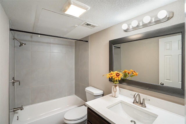 full bathroom with vanity, tiled shower / bath, toilet, and a textured ceiling