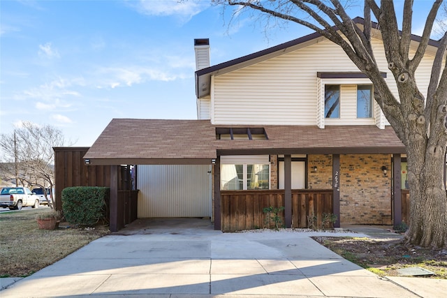 view of front of house with a carport, driveway, a chimney, and a shingled roof