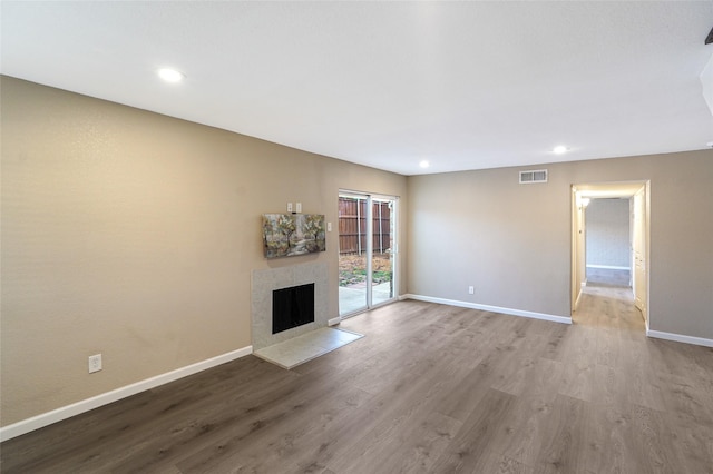 unfurnished living room featuring a tiled fireplace and light hardwood / wood-style flooring