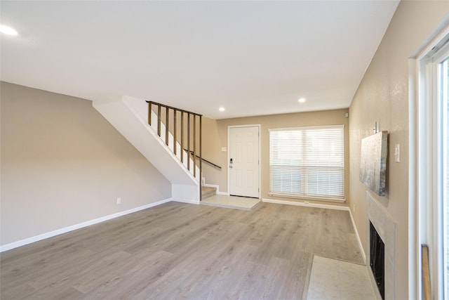 2658 Via Valencia, Carrollton, TX 75006 - unfurnished living room with light wood-type flooring, recessed lighting, stairs, baseboards, and a fireplace with flush hearth