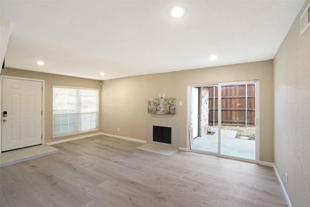 2658 Via Valencia, Carrollton, TX 75006 - unfurnished living room with a fireplace with flush hearth, light wood-style flooring, baseboards, and recessed lighting